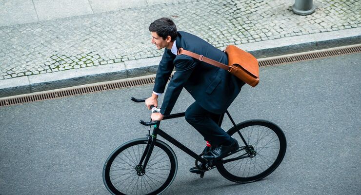 Young man wearing business suit while riding an utility bicycle